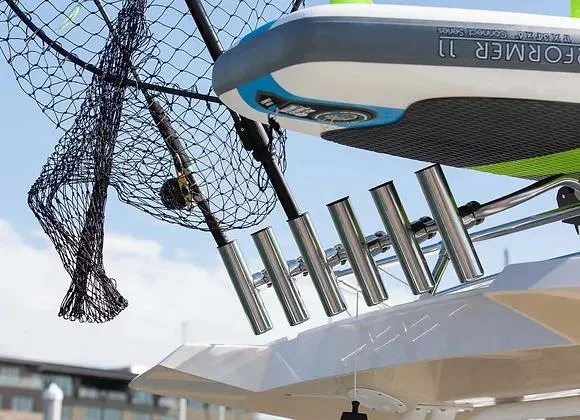 Slide: The Image of 2025 Solara 250 Center Walkaround fishing rod holders and net, docked under clear sky. - 7