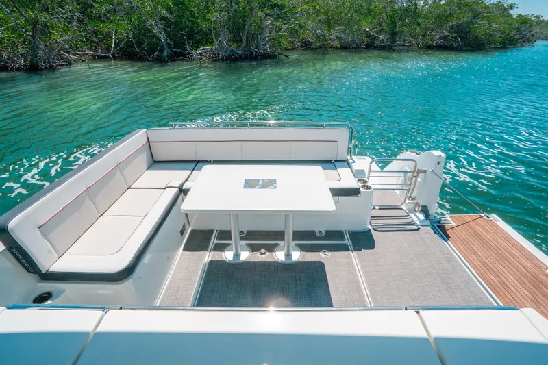 Slide: The Image of 2021 Jeanneau Leader 12.5 WA boat with spacious seating and table on turquoise water. - 10