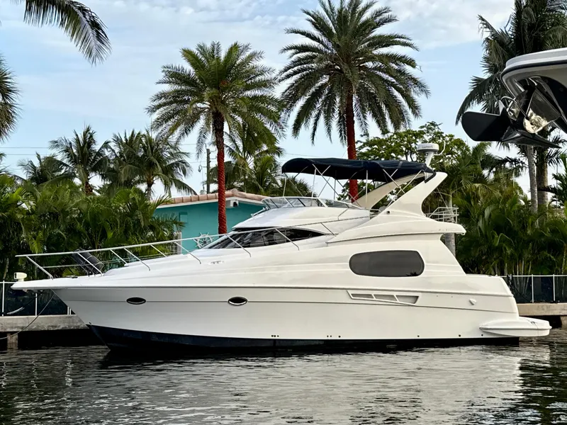 Slide: The Image of 2001 Silverton 410 Sport Bridge yacht docked near palm trees. - 2