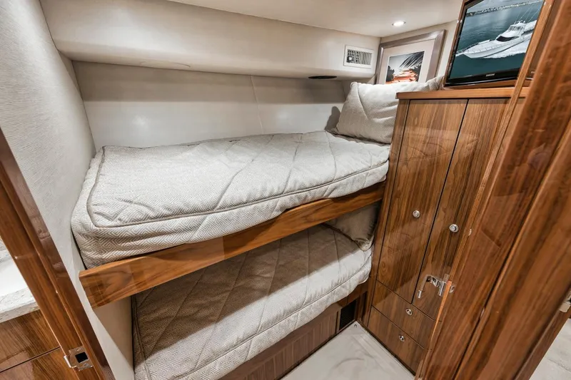 Slide: The Image of Interior of 2019 Viking 68 Convertible yacht with bunk beds and wooden cabinetry. - 33