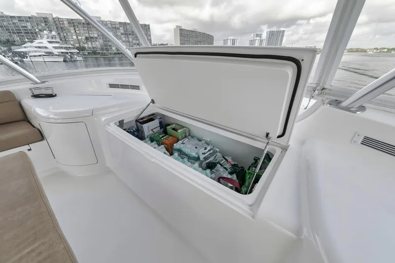 Slide: The Image of 2019 Viking 68 Convertible yacht with open storage compartment, stocked with beverages, docked near cityscape. - 47