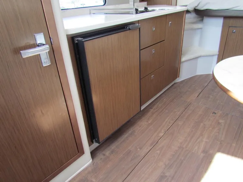 Slide: The Image of Interior of 2020 Cruisers Yachts 35 Express, featuring wooden cabinetry and compact kitchen area. - 36