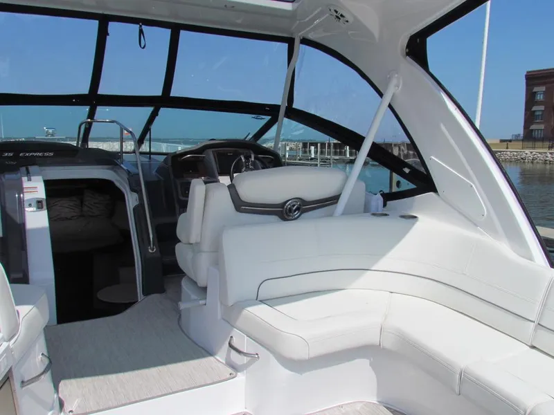 Slide: The Image of 2020 Cruisers Yachts 35 Express interior with white seating and helm, docked by the water. - 47