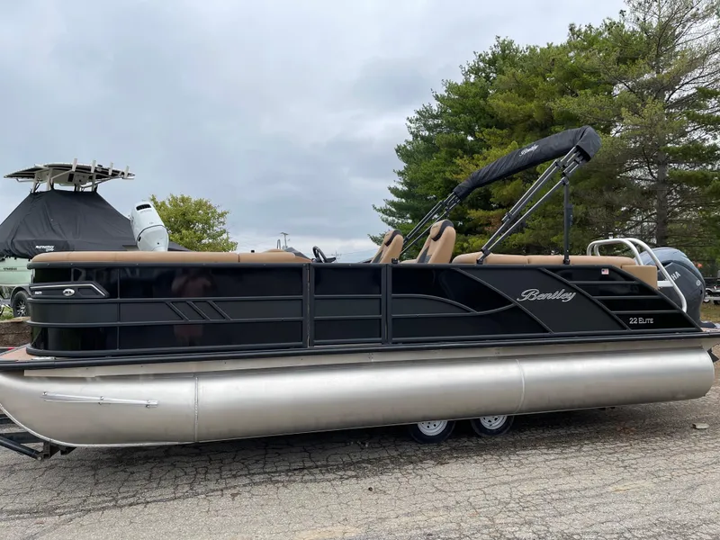 Slide: The Image of 2025 Bentley Pontoons Elite 223 Admiral, black exterior, parked on a trailer, overcast sky. - 4