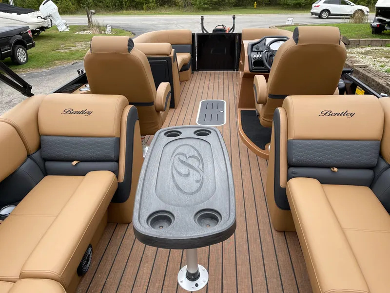 Slide: The Image of 2025 Bentley Pontoons Elite 223 Admiral interior with tan seating and central table. - 8