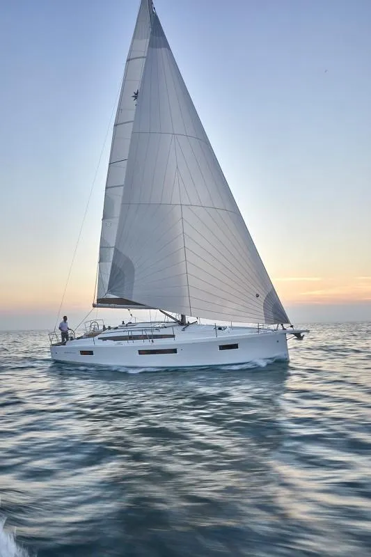 Slide: The Image of 2025 Jeanneau Sun Odyssey 410 sailing at sunset on calm waters. - 21