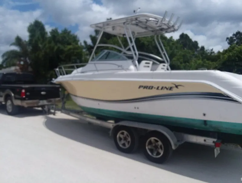 Slide: The Image of 2006 Pro-Line 24 Walk boat on trailer, hitched to a truck, outdoors. - 16