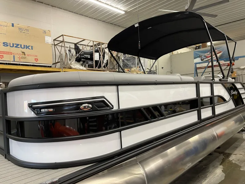 Slide: The Image of 2025 Bentley Pontoons Elite 253 Swingback in showroom, featuring sleek design and black canopy. - 3