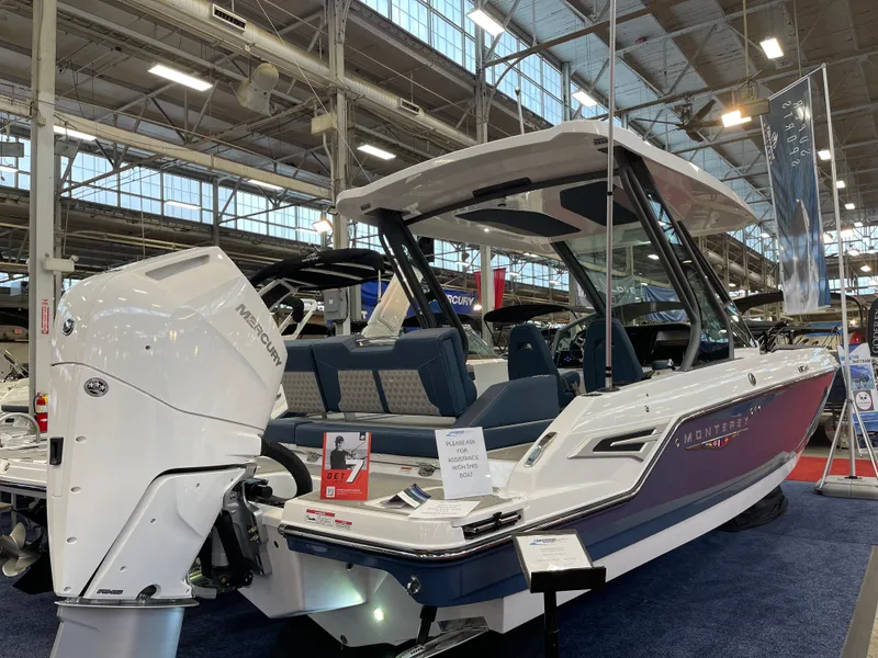 Slide: The Image of 2025 Monterey Elite 27 OB boat displayed indoors with powerful outboard motor. - 1