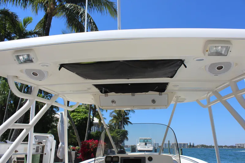 Slide: The Image of 2008 Pursuit S 310 Sport boat canopy with speakers and lights, docked near palm trees. - 15
