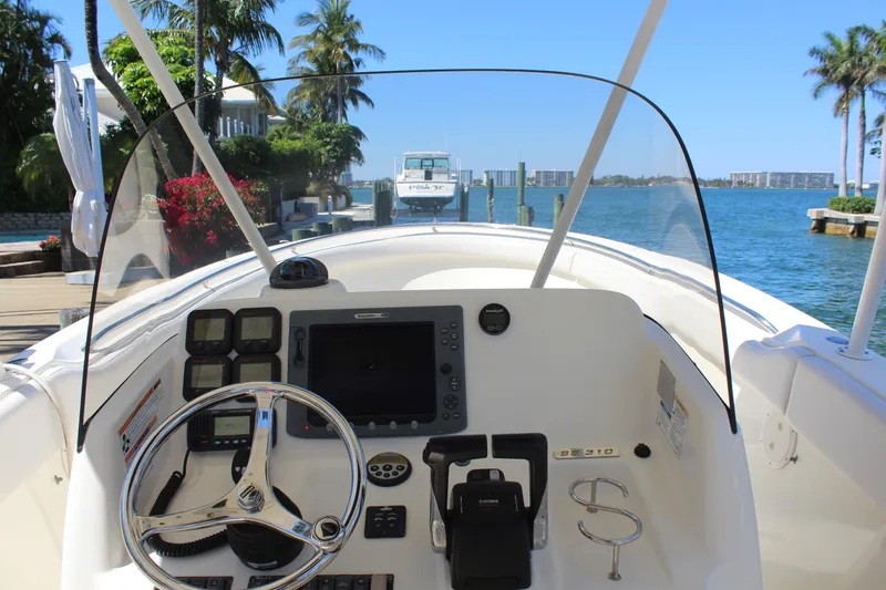 Slide: The Image of 2008 Pursuit S 310 Sport boat dashboard with steering wheel, controls, and waterfront view. - 16