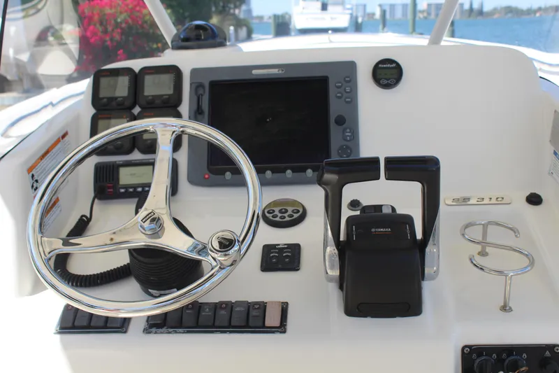Slide: The Image of 2008 Pursuit S 310 Sport boat dashboard with steering wheel and navigation controls. - 19