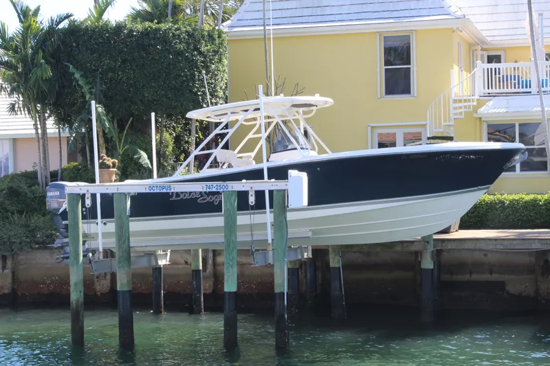 Slide: The Image of 2008 Pursuit S 310 Sport boat docked near a yellow house, surrounded by greenery. - 2