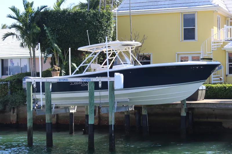 Slide: The Image of 2008 Pursuit S 310 Sport boat docked near a yellow house with lush greenery. - 3