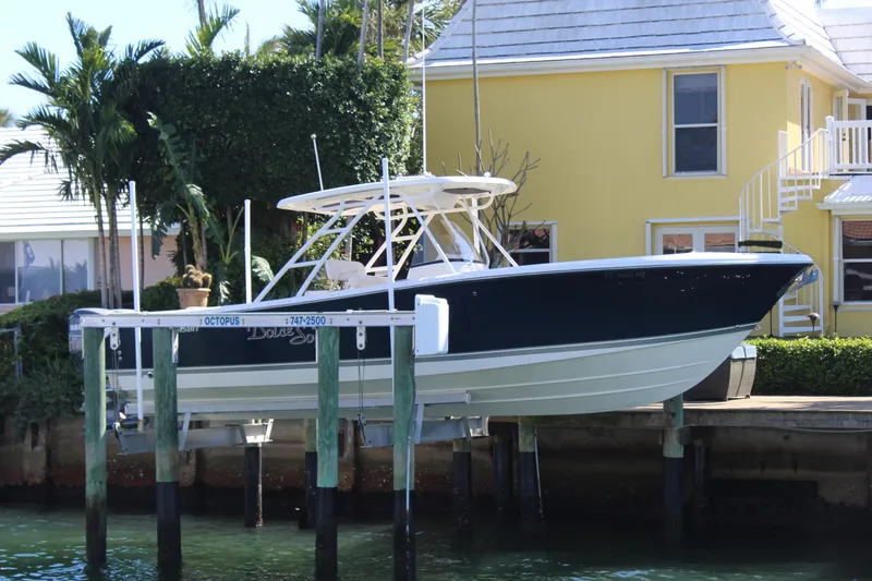 Slide: The Image of 2008 Pursuit S 310 Sport boat docked near a yellow house with lush greenery. - 4
