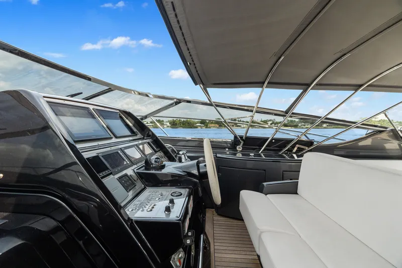 Slide: The Image of 2015 Riva 63 Virtus yacht cockpit with modern controls and white seating under a clear blue sky. - 20