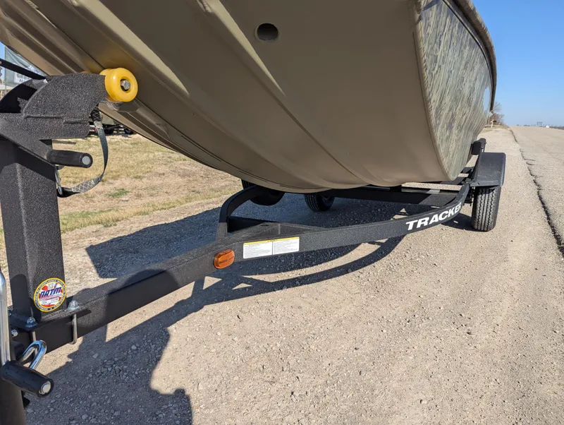 Slide: The Image of 2025 Tracker Grizzly 1650 T Prairie Wings Edition boat on a trailer, parked on a gravel road. - 10