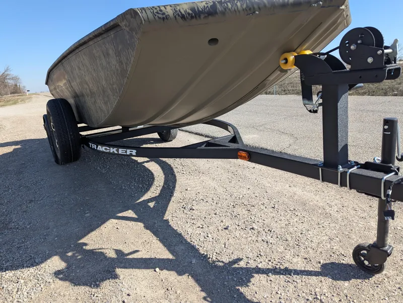 Slide: The Image of 2025 Tracker Grizzly 1650 T Prairie Wings Edition boat on a trailer, parked on gravel. - 9