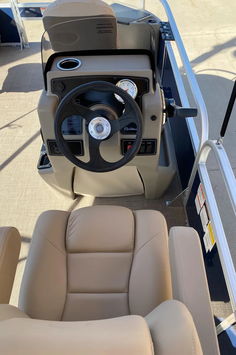 Slide: The Image of 2025 Sun Tracker Bass Buggy 18 DLX boat interior with steering wheel and beige seating. - 6