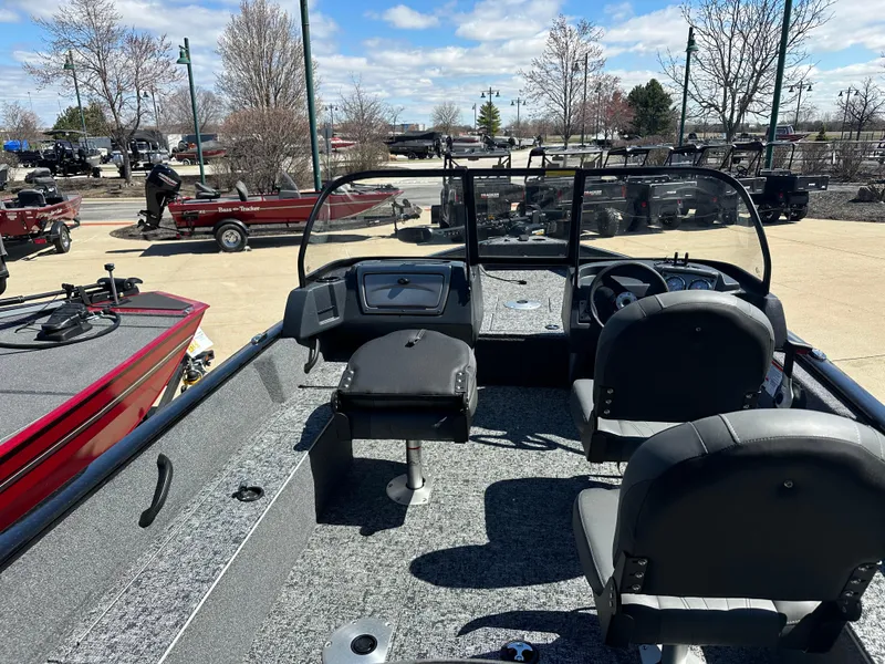 Slide: The Image of 2025 Tracker Pro Guide V-16 WT boat interior with seating and dashboard, parked outdoors. - 2