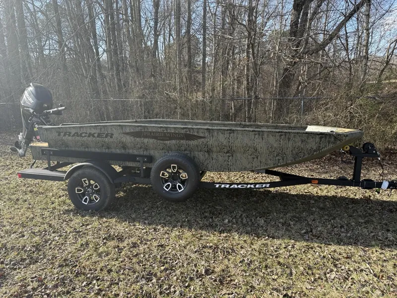 Slide: The Image of 2025 Tracker Grizzly 1650 T Prairie Wings Edition boat on trailer, parked outdoors. - 2