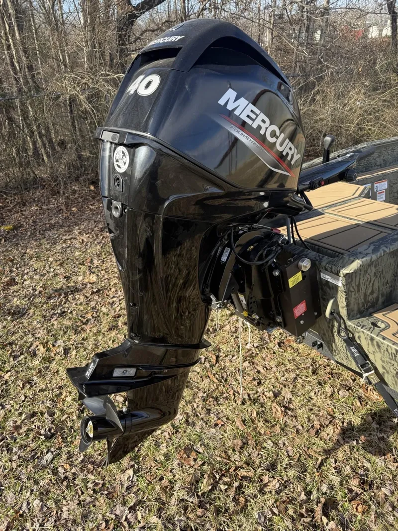 Slide: The Image of 2025 Tracker Grizzly 1650 T Prairie Wings Edition with Mercury outboard motor in wooded area. - 3