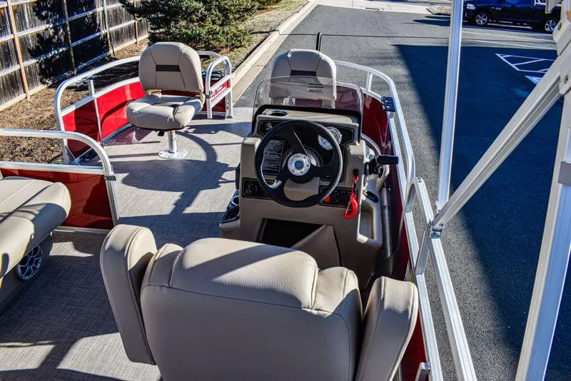 Slide: The Image of 2025 Sun Tracker Bass Buggy 16 XL Select pontoon boat interior with beige seating and steering console. - 2