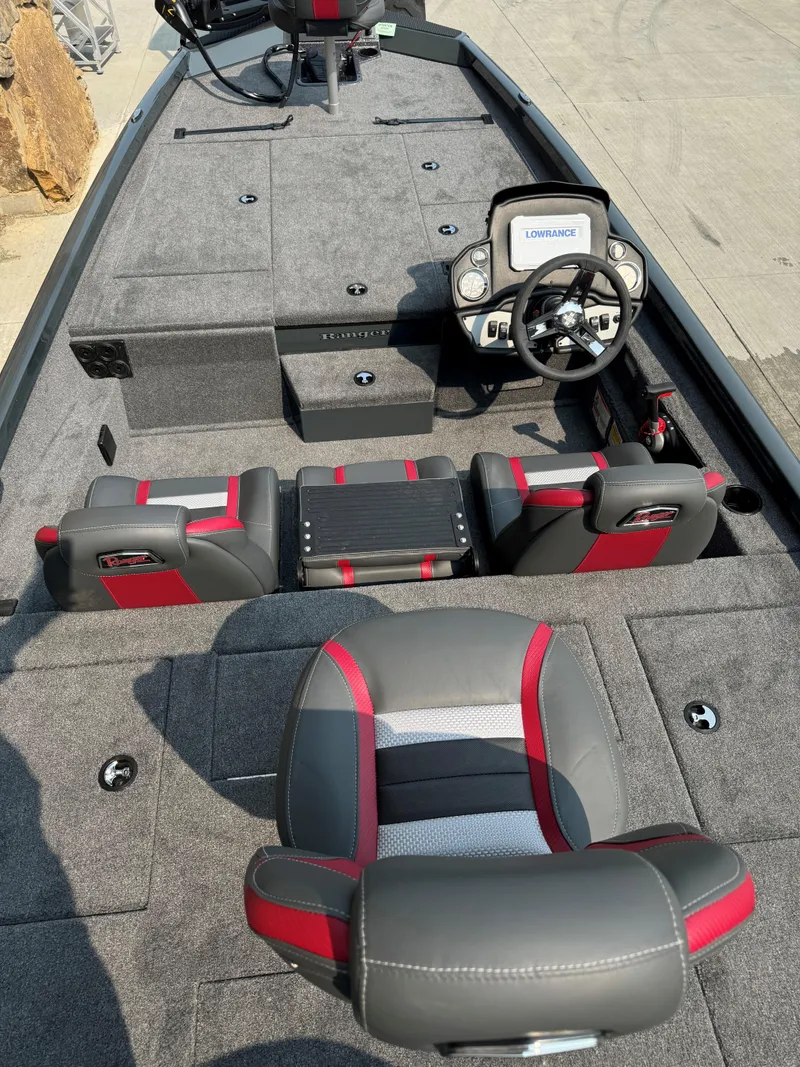 Slide: The Image of 2025 Ranger RT198P boat interior with gray and red seating, steering console, and carpeted deck. - 2