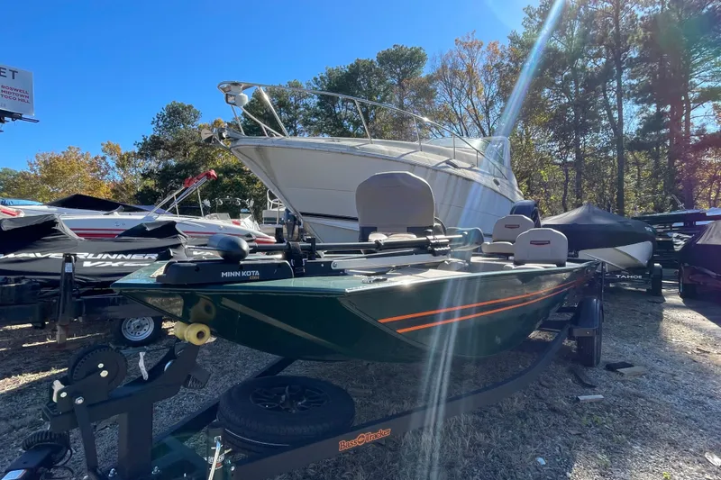 Slide: The Image of 2025 Tracker Bass Tracker Classic Limited boat on trailer, surrounded by other boats, in a wooded area. - 40