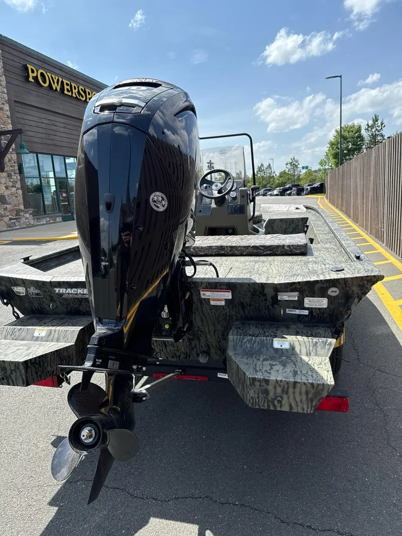 Slide: The Image of 2025 Tracker Grizzly 1860 CC boat with powerful outboard motor, parked outdoors. - 2