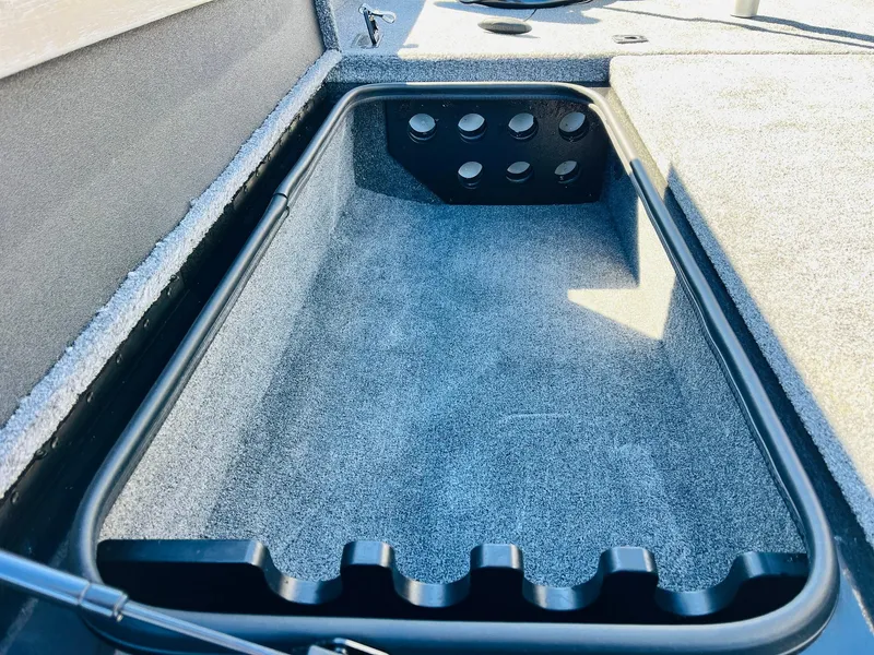 Slide: The Image of 2024 Ranger RT198P boat storage compartment with rod holders and carpeted interior. - 16