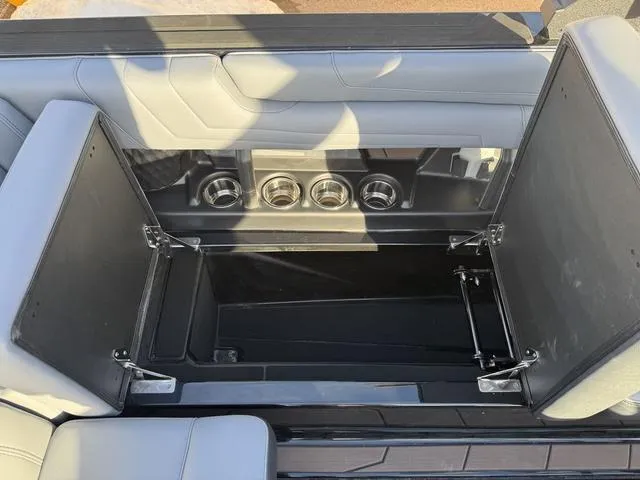 Slide: The Image of 2025 Malibu 25 LSV boat storage compartment with cup holders and sleek seating design. - 15