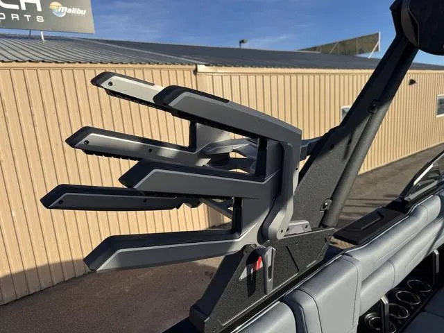 Slide: The Image of 2025 Malibu 25 LSV boat with a sleek wakeboard rack in a sunny outdoor setting. - 16