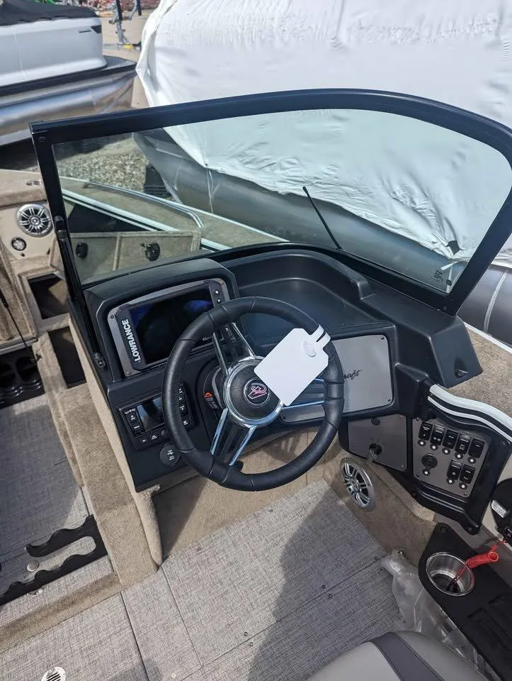 Slide: The Image of 2024 Alumacraft Trophy 185 boat dashboard with steering wheel and control panel. - 14