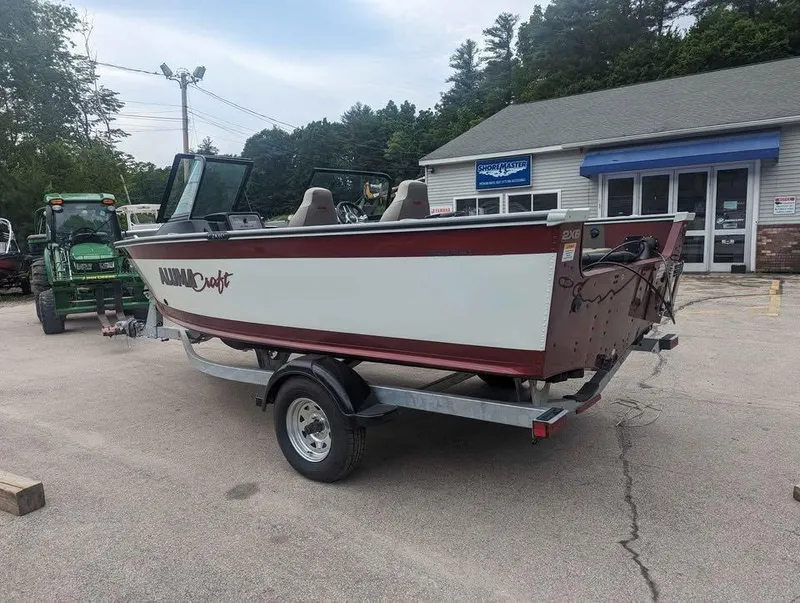 Slide: The Image of 2024 Alumacraft Trophy 185 boat on trailer, parked outside a building. - 5