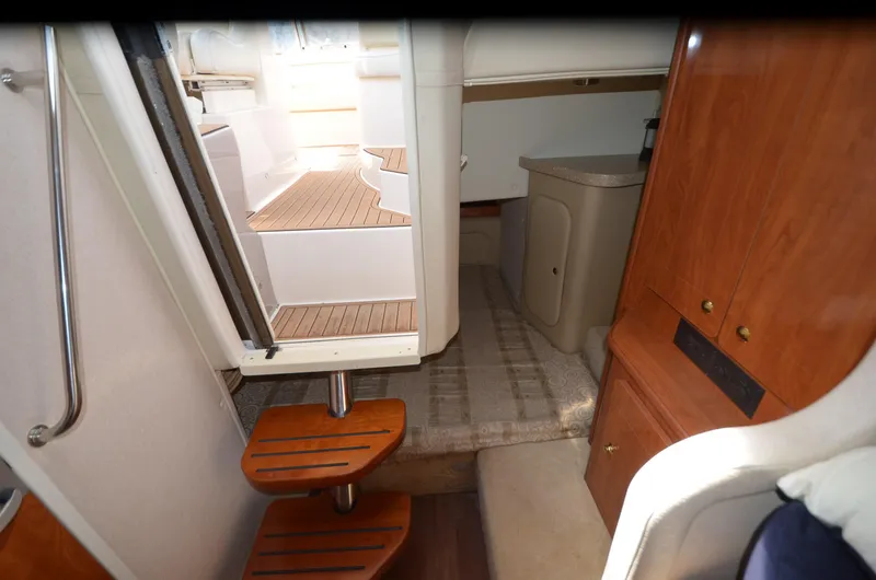 Slide: The Image of Interior of 2005 Rinker Fiesta Vee 300 EC boat, featuring wooden steps and compact cabin space. - 16