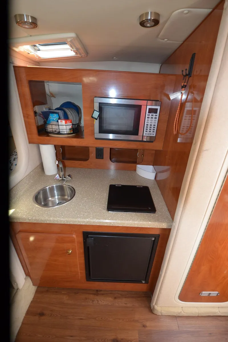 Slide: The Image of 2005 Rinker Fiesta Vee 300 EC galley with microwave, sink, and compact fridge. - 20