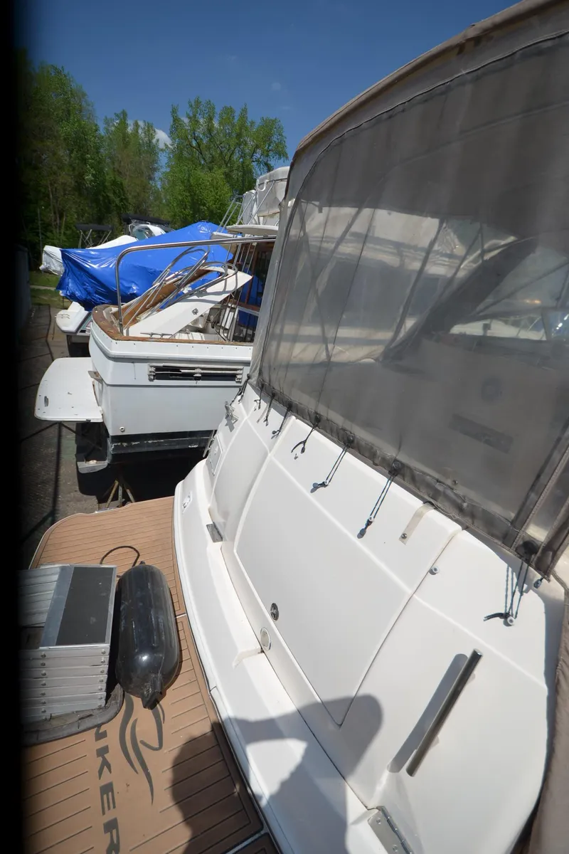 Slide: The Image of 2005 Rinker Fiesta Vee 300 EC boat docked with covered deck, surrounded by greenery. - 21