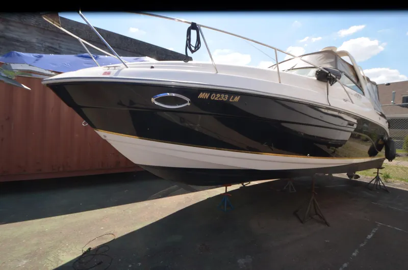 Slide: The Image of 2005 Rinker Fiesta Vee 300 EC boat on stands, black and white hull, outdoor setting. - 4