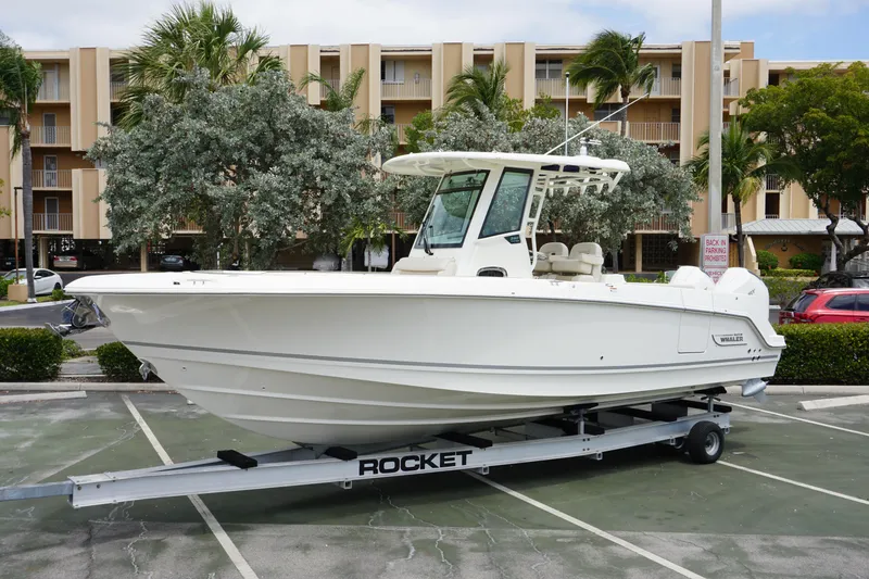 The Image of 2025 Boston Whaler 280 Outrage boat on trailer in parking lot. - 0