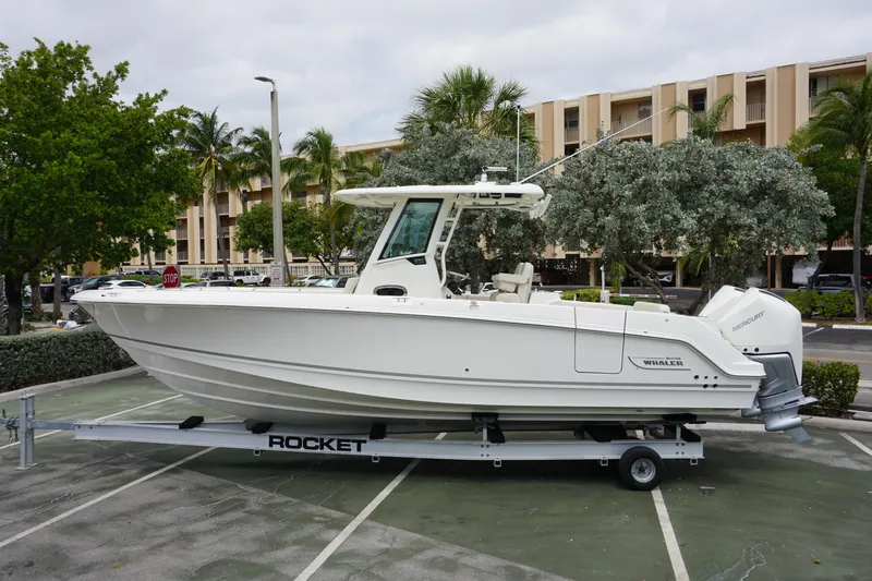 Slide: The Image of 2025 Boston Whaler 280 Outrage boat on trailer in parking lot. - 1