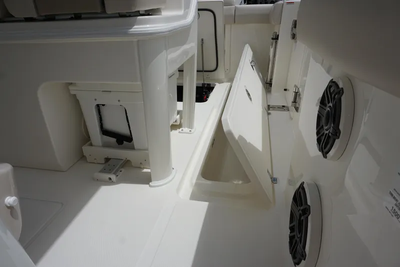 Slide: The Image of 2025 Boston Whaler 280 Outrage interior with open storage compartment and speakers. - 12