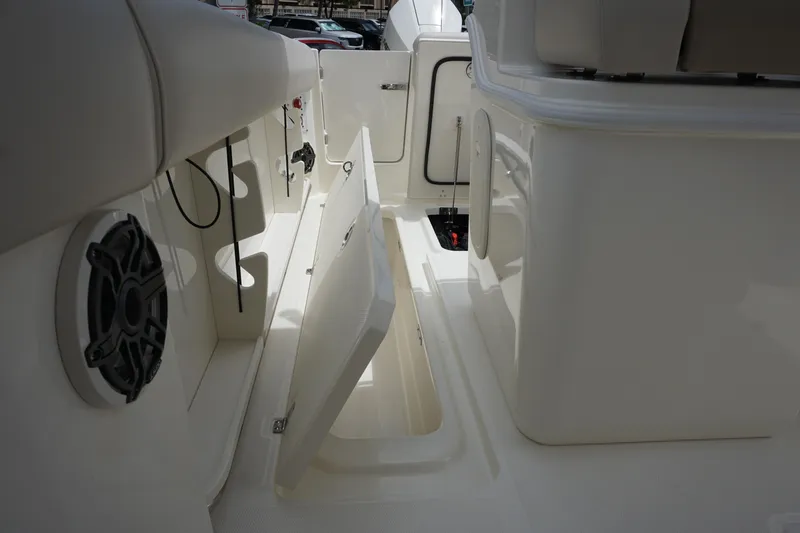 Slide: The Image of 2025 Boston Whaler 280 Outrage interior with open storage compartment and speaker. - 13