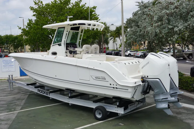 Slide: The Image of 2025 Boston Whaler 280 Outrage boat on trailer, parked outdoors. - 2