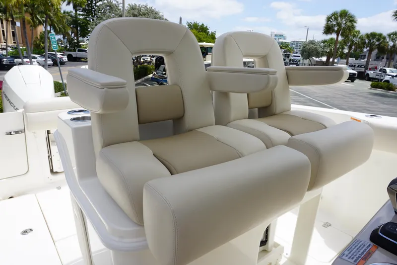 Slide: The Image of 2025 Boston Whaler 280 Outrage boat seats, featuring plush beige upholstery and armrests. - 27