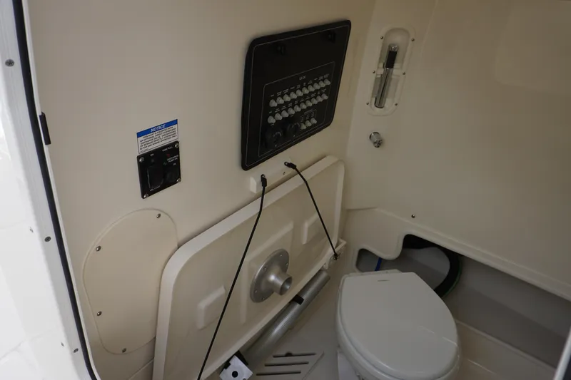 Slide: The Image of 2025 Boston Whaler 280 Outrage interior with control panel and marine toilet. - 38