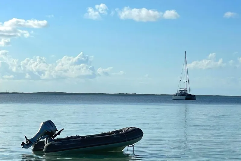 Slide: The Image of Inflatable boat and Lagoon 450 F catamaran on calm sea under blue sky. - 11