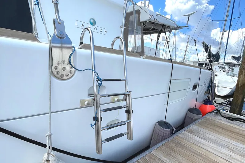 Slide: The Image of 2016 Lagoon 450 F catamaran docked, featuring a stainless steel ladder and clear blue skies. - 13