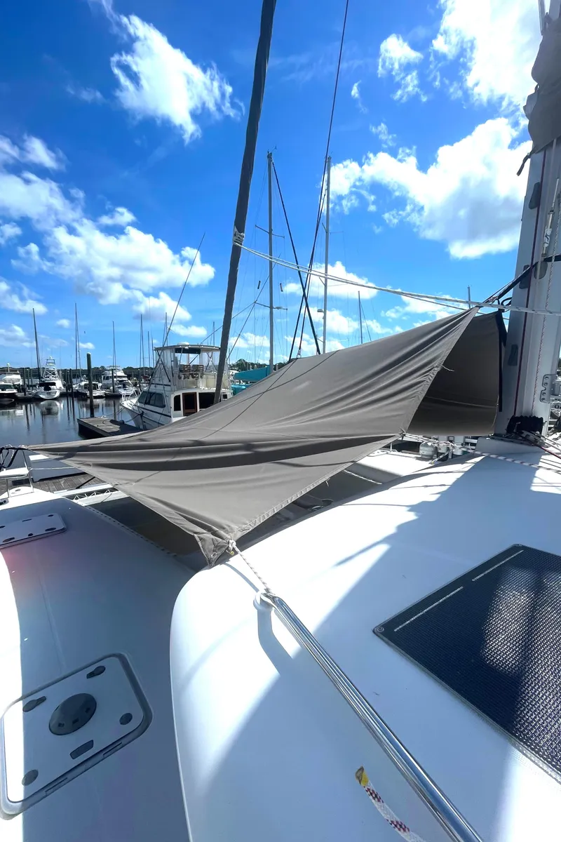 Slide: The Image of 2016 Lagoon 450 F catamaran with sunshade, docked at marina under blue sky. - 16