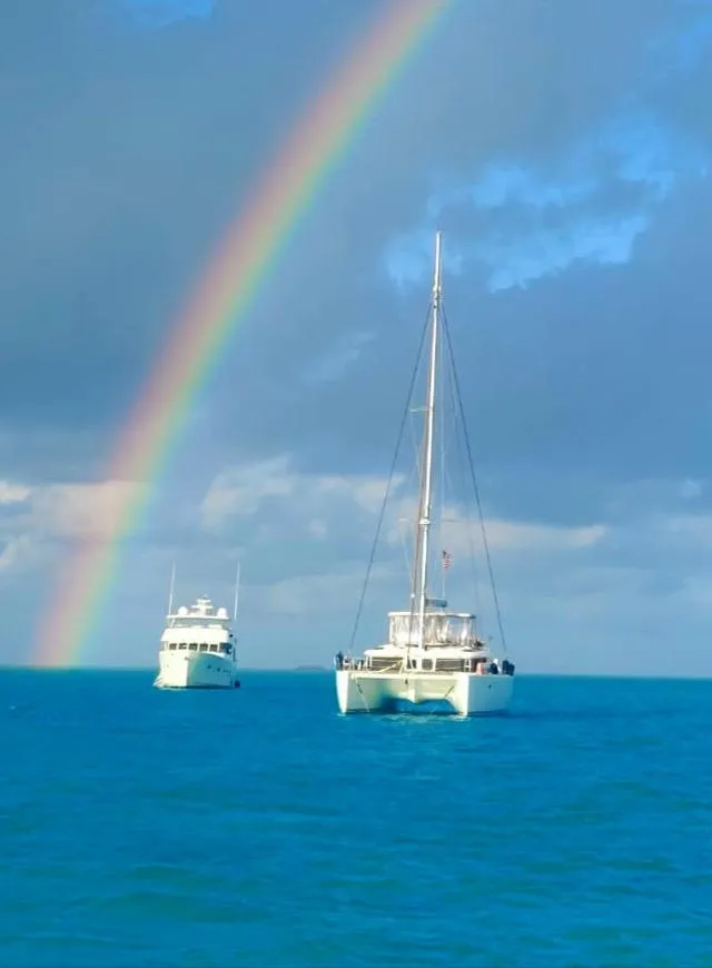 Slide: The Image of Catamaran Lagoon 450 F sailing under a vibrant rainbow on the ocean. - 3